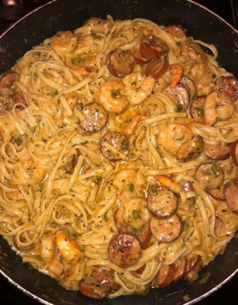 A bowl of Cajun shrimp pasta with sausage, topped with grated Parmesan cheese