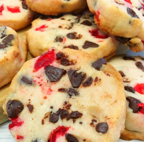 A plate of maraschino cherry Christmas shortbread cookies with a cherry on top of each one.