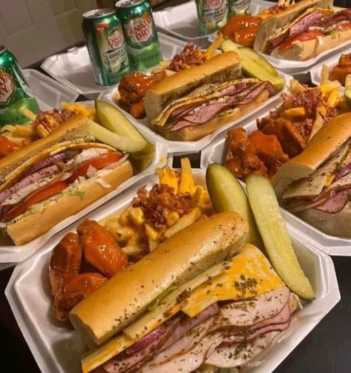 A delicious deli sub sandwich filled with roast beef, smoked turkey, and crispy bacon on a fresh roll, paired with sweet wings and cheesy fries