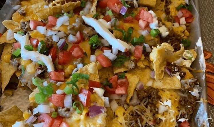Epic Beef Nachos Supreme: A delicious platter of nachos topped with seasoned ground beef, melted cheese, diced tomatoes, and green onions.