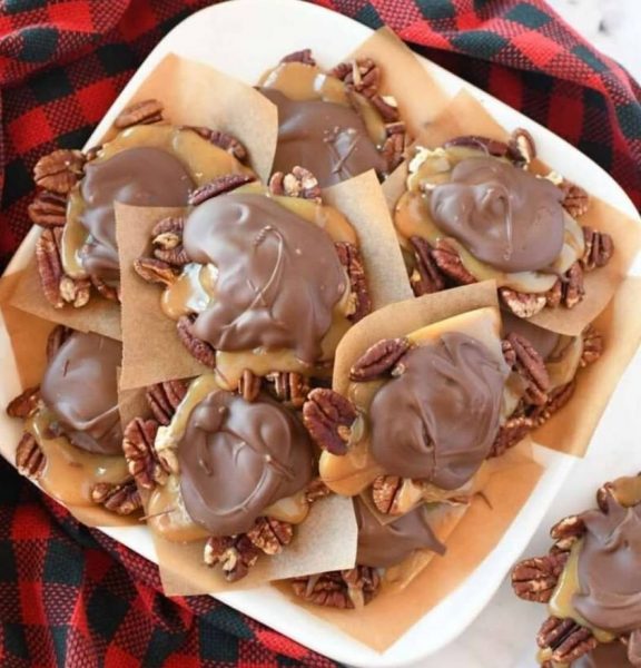 A close-up of homemade turtle candy with pecans and caramel on a parchment paper