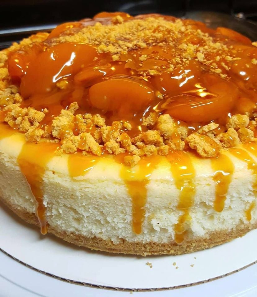A slice of Peach Cobbler Cheesecake with a flaky crust, creamy filling, and sweet peach topping