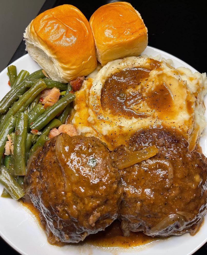 Salisbury steak with onion gravy and sides on a plate