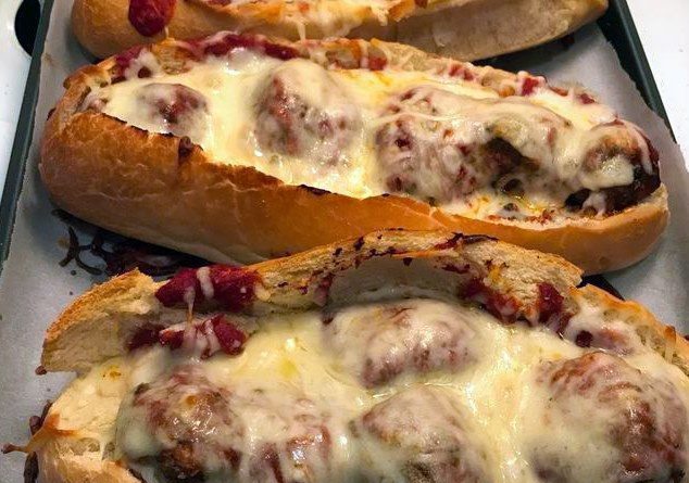 "Meatball Boats - Juicy ground beef meatballs on a bed of melted Asiago cheese in a perfectly hollowed hoagie roll, a gastronomic delight.