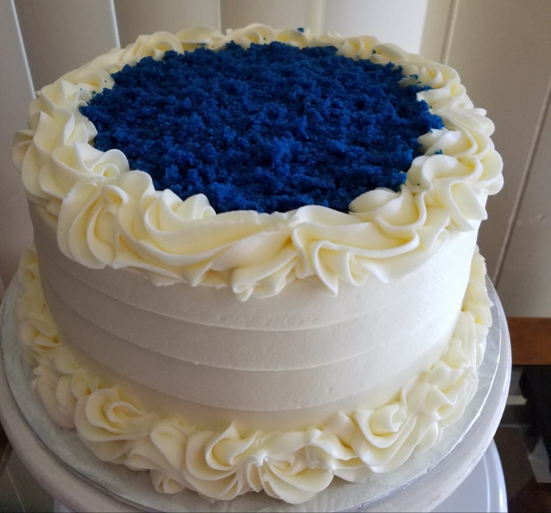 Blue and white layered cake with cream cheese frosting on a cake stand