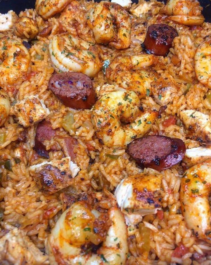 A pot of homemade jambalaya with chicken, sausage, and shrimp being spooned out of a pot