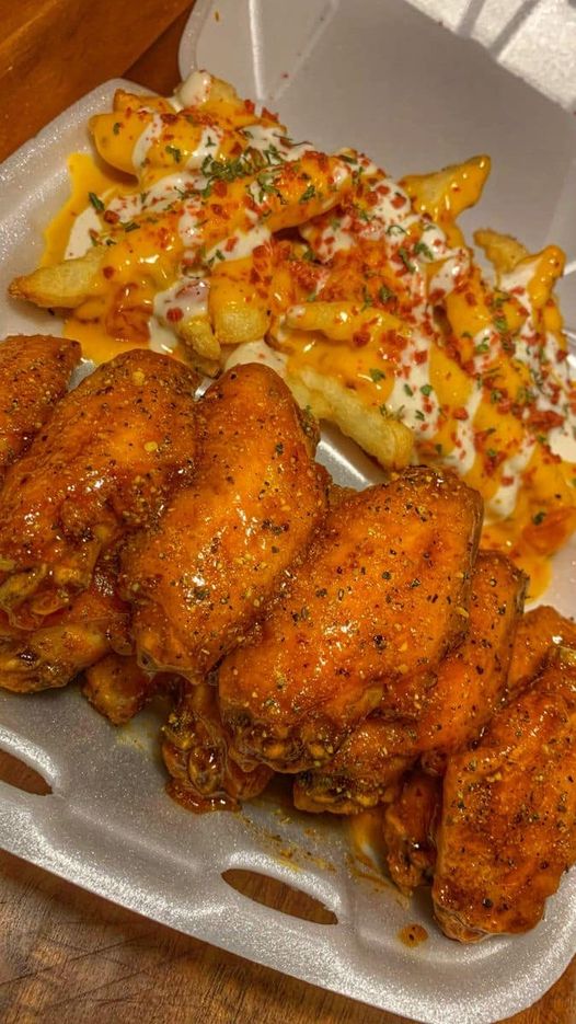 Plate of lemon pepper hot wings with a side of bacon cheese fries