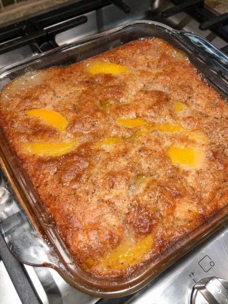 A delicious homemade peach cobbler with a golden brown crust, topped with fresh peaches.