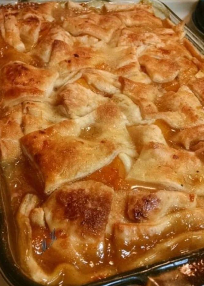 A cobbler dish filled with juicy peaches and topped with a triple crust