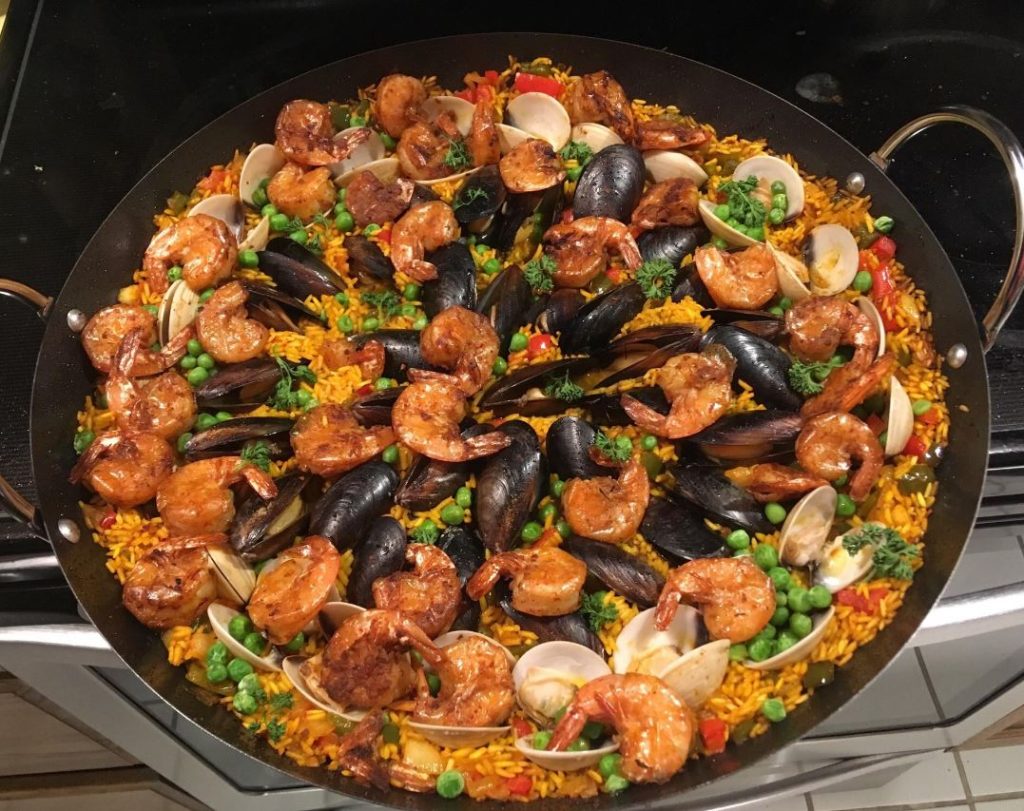 A close-up of a serving of Seafood Paella, showing the crispy layer on the bottom and the fresh seafood on top.