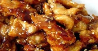 Crock Pot Sesame Chicken - Golden honey, bourbon, and soy sauce-infused chicken bites, sprinkled with sesame seeds, served over rice.