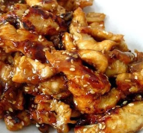 Crock Pot Sesame Chicken - Golden honey, bourbon, and soy sauce-infused chicken bites, sprinkled with sesame seeds, served over rice.