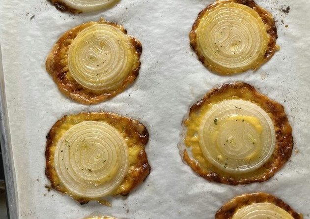 Cheesy Onion Crisps on a white plate – a crispy, golden delight topped with cheddar cheese and ranch seasoning.