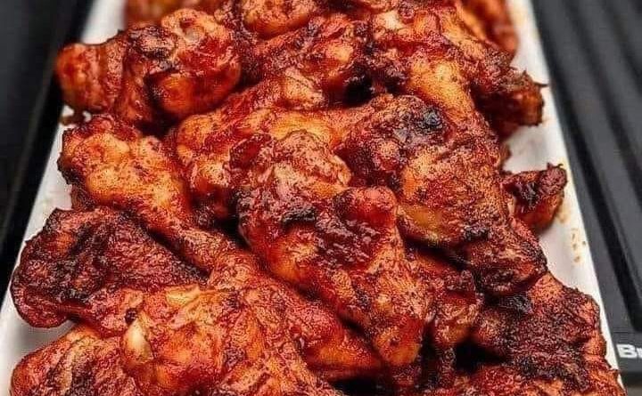 Smoked chicken wings arranged on a grill, showcasing a perfect blend of spices and a tantalizing crispy finish.