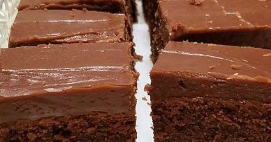 Close-up photo of warm, freshly baked chocolate fudge brownies with rich, crackly tops and gooey centers, cut into squares on a serving plate.