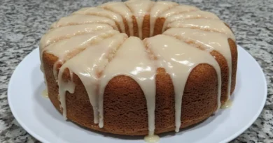 A photo of a slice of lemon cream cheese pound cake on a white plate.
