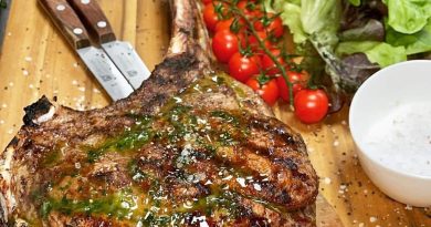 thick-cut Tomahawk steak seasoned with herbs and spices, sizzling on a hot grill with flames leaping up around it.