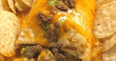 A baking dish filled with golden brown beef and cheese sanchiladas smothered in red enchilada sauce.