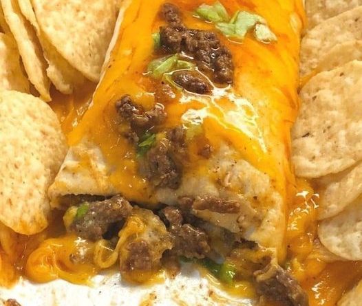 A baking dish filled with golden brown beef and cheese sanchiladas smothered in red enchilada sauce.