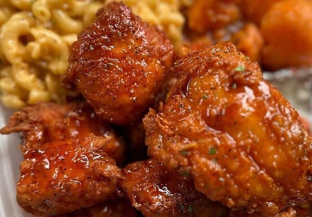 A plate with Cajun-seasoned salmon bites, creamy macaroni and cheese, and roasted yam slices.