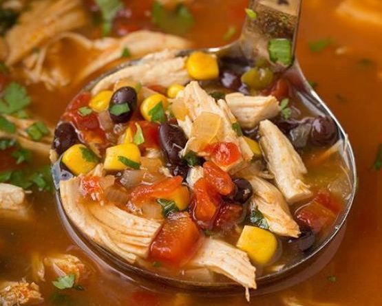 Crock Pot filled with chicken, vegetables, and broth for Chicken Tortilla Soup.