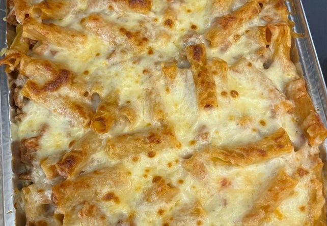 A bubbling hot baking dish filled with rigatoni pasta in a creamy tomato sauce, topped with melted mozzarella cheese and a sprinkling of fresh parsley.