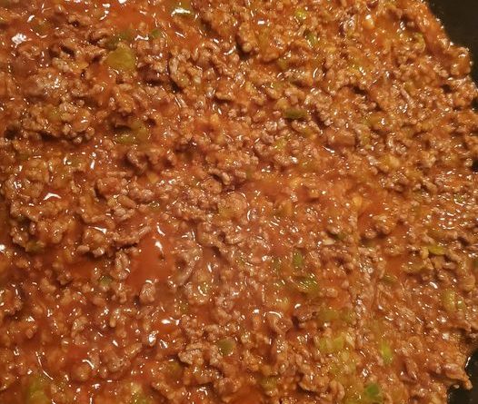 A close-up photo of a hamburger bun overflowing with a savory Sloppy Joe mixture made with ground beef, peppers, onions, and salsa.