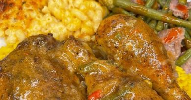 Smothered chicken pieces in a savory gravy on a bed of fluffy white rice, surrounded by baked mac and cheese, green beans with smoked turkey, and a slice of cornbread.