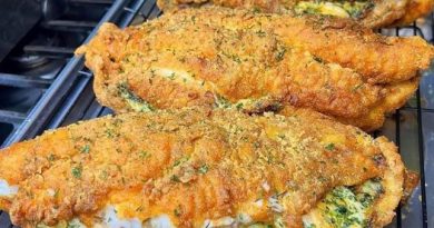 A golden brown baked catfish with a creamy cheese, spinach, and shrimp stuffing visible through the top.