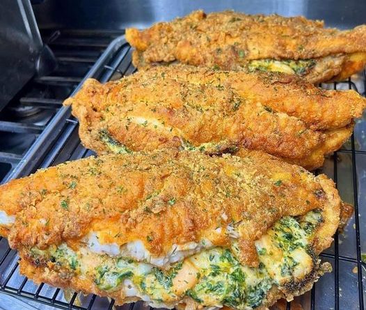 A golden brown baked catfish with a creamy cheese, spinach, and shrimp stuffing visible through the top.