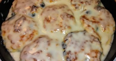 A close-up photo of golden brown sweet blueberry biscuits on a baking sheet. Fresh blueberries are visible throughout the fluffy biscuits.