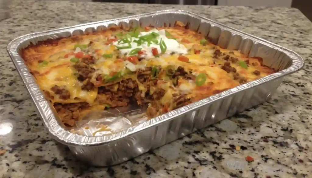 Walking Taco Casserole – Layers of seasoned beef, beans, and cheese in a 9x13 inch baking dish, ready for a delicious bake.