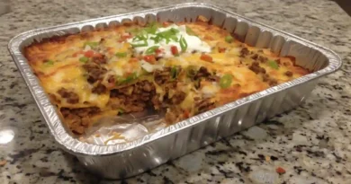 Walking Taco Casserole – Layers of seasoned beef, beans, and cheese in a 9x13 inch baking dish, ready for a delicious bake.