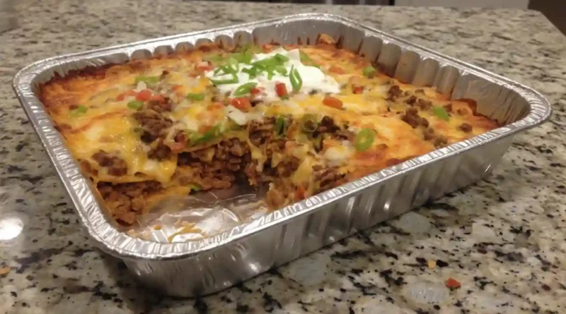 Walking Taco Casserole – Layers of seasoned beef, beans, and cheese in a 9x13 inch baking dish, ready for a delicious bake.