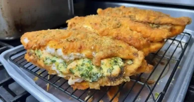 A golden brown baked catfish with a creamy cheese, spinach, and shrimp stuffing visible through the top.